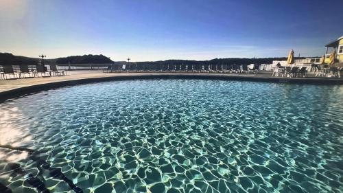 a large pool of clear blue water with chairs at No Putts Given. Cozy home on Par 4, free Golf Cart and Pool access in Osage Beach