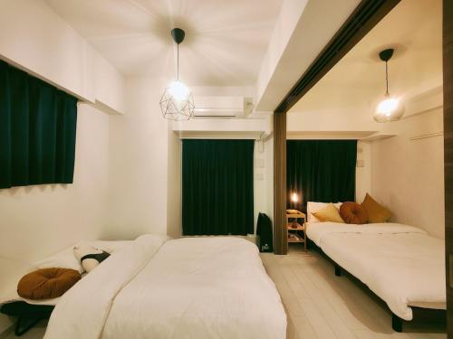 two beds in a room with green curtains at 無料駐車場付き恵美須町駅から190mあたたかくておしゃれな家 in Osaka