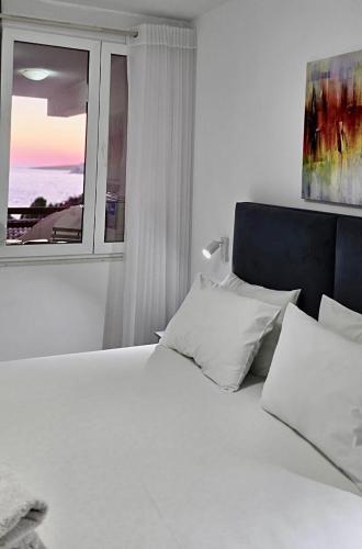 a bedroom with a white bed and a window at Sunny Bay Apartments in Sarandë