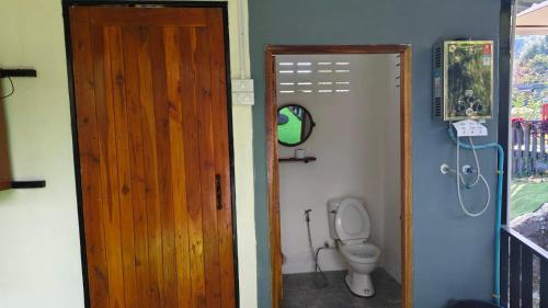 a bathroom with a toilet and a wooden door at อินทนนท์ บ้านพักเล่าจู Inthanon Laoju House in Ban Na Yang
