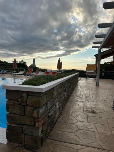 a stone retaining wall next to a swimming pool at Agri Resort Masusa in Aquara