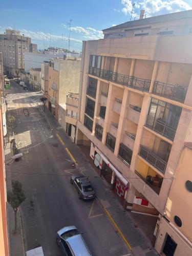 a city street with cars parked in front of a building at Apartamento completo in Burriana