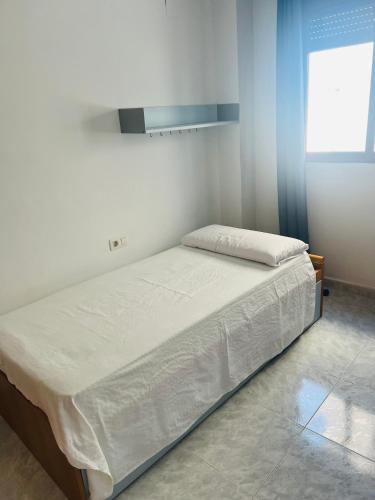 a bed in a room with white walls and a window at Apartamento completo in Burriana