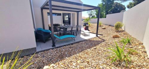 un patio con tavolo e sedie in una casa di "LE BONHEUR EST DANS LE VEILLON" Maison neuve 3 chambres de 2025, 7 personnes, avec jacuzzi 6 personnes et climatisation réversible a Talmont