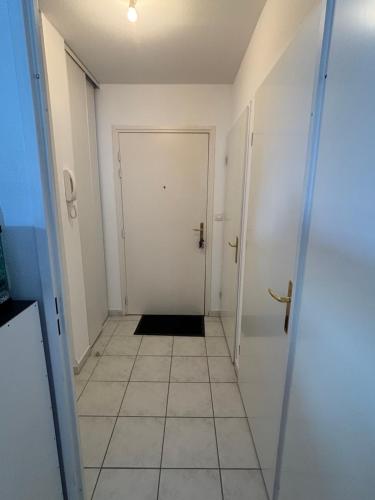 - un couloir avec une porte blanche et du carrelage dans l'établissement Appartement 2 personnes sur Amiens, à Amiens