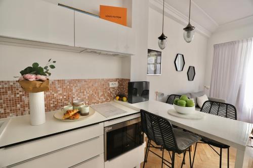 - une cuisine avec des comptoirs blancs et une table avec des chaises dans l'établissement Chic 1-bedroom apartment steps away from La Croisette, à Cannes