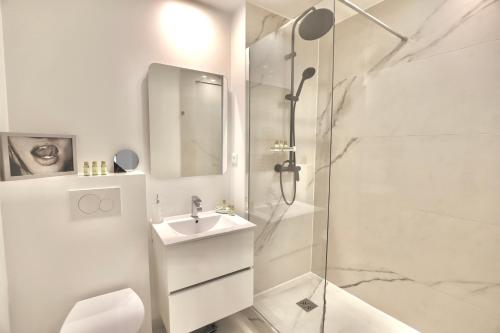 une salle de bain blanche avec une douche et un lavabo dans l'établissement Chic 1-bedroom apartment steps away from La Croisette, à Cannes