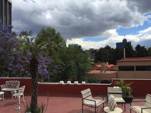 a patio with chairs and tables on a roof at Casa Corp Boutique Suites in Condesa in Mexico City
