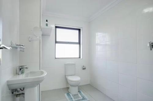 a white bathroom with a toilet and a sink at Spearhead on Lake Accommodation-5A in Marina da Gama