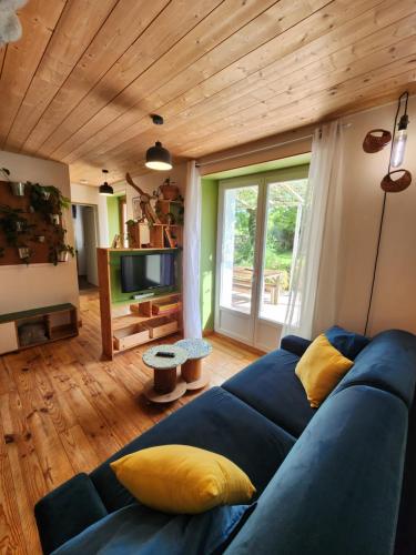 - un canapé bleu dans le salon avec un plafond en bois dans l'établissement Domaine Langelet - Insolite 40