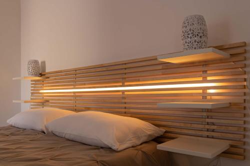 a bed with a wooden head board with two pillows at Casa Caminari in Grottaglie