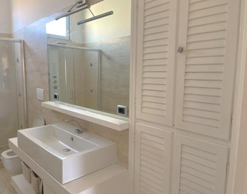 ein weißes Badezimmer mit Waschbecken und Spiegel in der Unterkunft LUNA SUL PORTO Seaview Apartment - Bright and Spacious Flat in Central Nettuno, Steps from the Marina, Beaches, and Train Station in Nettuno