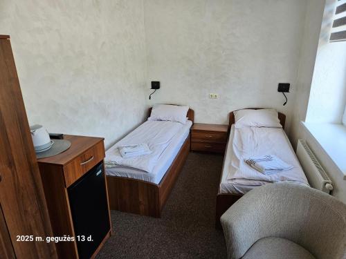 two beds in a room with a chair and a desk at Pas Nerijų in Skuodas