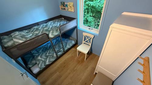 a small room with a bunk bed and a chair at Vakantiehuisje Sinneblom in Grou