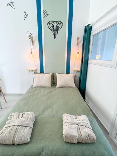 a bedroom with a green bed with towels on it at Blue Bergamote Syros in Ermoupoli
