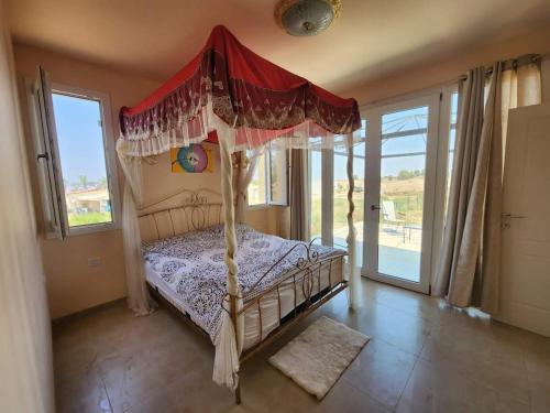 a bedroom with a canopy bed in a room with windows at Golden House in Kidmat Tsvi