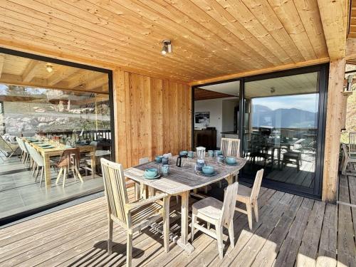 une table et des chaises en bois sur une terrasse en bois dans l'établissement Chalet 8 pièces avec spa, sauna, 15 pers, à 800m des pistes, Notre-Dame-de-Bellecombe - FR-1-595-1, à Notre-Dame-de-Bellecombe
