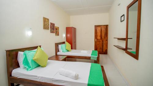 une petite chambre avec deux lits et un miroir dans l'établissement Royal Heritage Resort, à Kandy