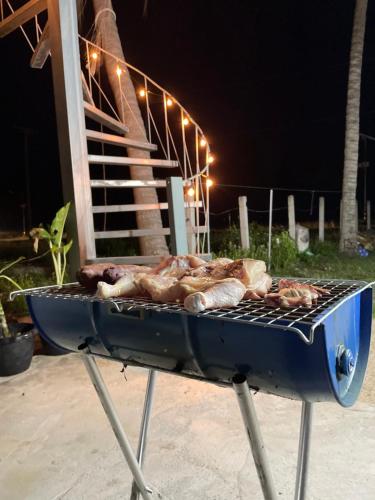 a grill with meat on top of it at night at Earnhomestay sichon in Ban Plai Thon