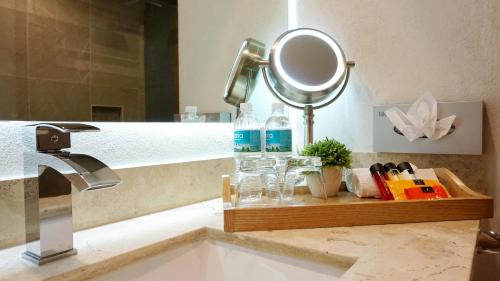 a bathroom sink with a mirror and a bottle of water at Hit Hoteles Aeropuerto Puebla in Huejotzingo