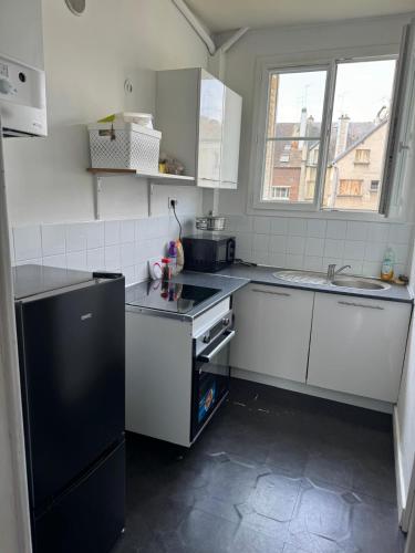 une cuisine avec des armoires blanches et un réfrigérateur noir dans l'établissement Chez Rami - Charmant T3 - Rue Jacoby, à Beauvais