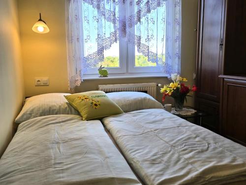 a bed in a bedroom with a window and flowers at Agroturystyka Gawryś pokoje in Sasino