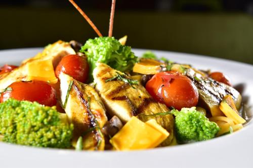 a plate of food with chicken broccoli and tomatoes at Hotel Montecarlo in Ibarra