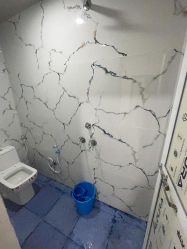 a bathroom with a toilet and a blue bucket at Winter Hotel at Ujjain in Ujjain