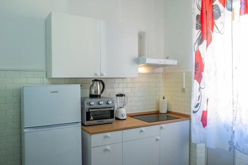 a kitchen with white cabinets and a white refrigerator at Casa Giorgia with Parking Space in Genova