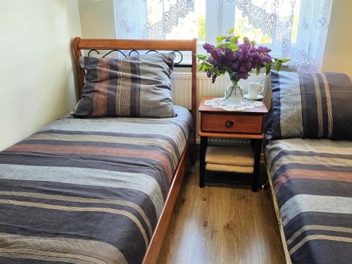 a bedroom with two beds and a table with a vase of flowers at Agroturystyka Gawryś pokoje in Sasino