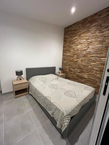 une chambre avec un lit et un mur de briques dans l'établissement Petit appartement de 35 m2 au Puig del Mas, à Banyuls-sur-Mer