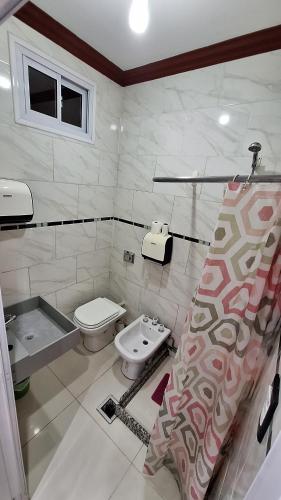 Un baño blanco con inodoro y lavabo. en Complejo Alicia, en General Gutiérrez
