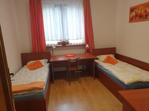 a room with two beds and a desk and a window at Studio Rynek Pułtusk in Pultusk