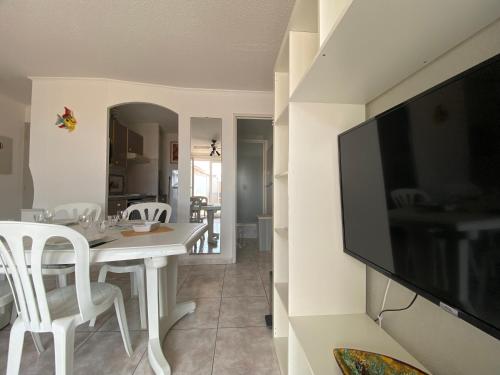 une salle à manger avec une table blanche et une télévision à écran plat dans l'établissement Appartement 50 m de la plage vue mer, à Sainte-Marie-la-Mer
