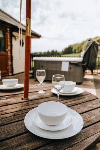 a wooden table with plates and wine glasses on it at Vale Farm Cottages in Brecon