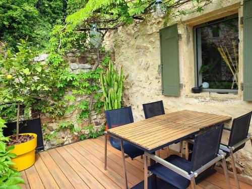 a wooden table and chairs on a wooden deck at un pied dans la forêt in La Capelle-et-Masmolène