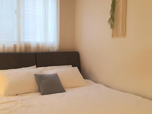 a bedroom with a bed with white pillows and a window at Soo Stay in Daegu