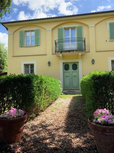a yellow house with a green door and some bushes at Dimora Umbra al civico 65 in Campello sul Clitunno