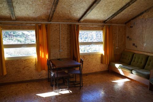 a room with a table and a couch and two windows at Tebulo Biodiv&Guest House in Khone