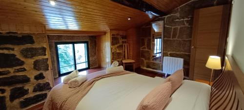 a bedroom with a bed in a room with a stone wall at Luz do Sil in Ourense