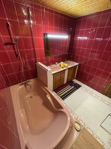 La salle de bains est pourvue de carrelage rouge, d'une baignoire et d'un lavabo. dans l'établissement Superbe maison familiale, à Les Sciauds