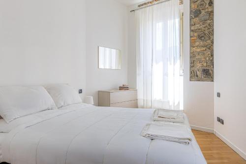 a white bed in a white bedroom with a window at River House Lenno - Tremezzina - Como Lake in Lenno