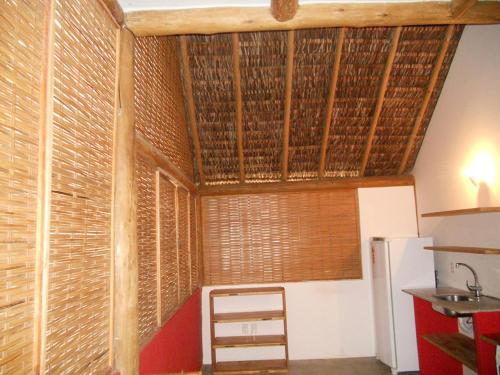 a room with wooden ceilings and a room with a refrigerator at Bed & Breakfast Casa Dos Cajueiros in Barra Grande