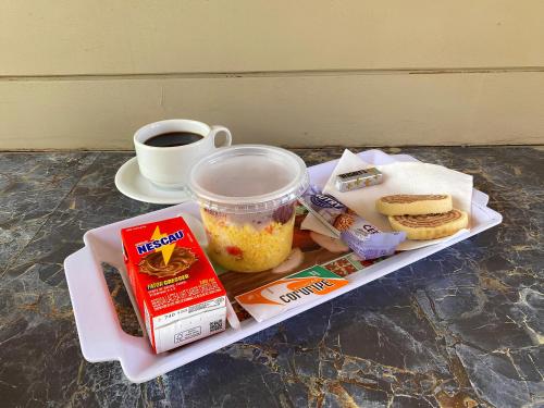 ein Tablett mit Essen, dazu eine Tasse Kaffee und eine Tasse Essen in der Unterkunft Flor de Lótus Privilege in Japaratinga