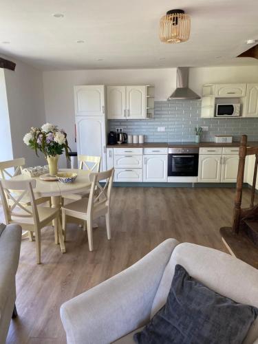 une cuisine et une salle à manger avec une table et des chaises dans l'établissement Les Rimpaudieres, à Saint-Rémy-en-Montmorillon