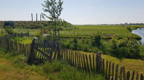 a wooden fence in a field next to a river at Gezellige caravan met weids uitzicht nabij Sneekermeer in Terzool