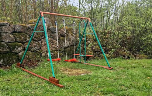 a swing set in a field with a stone wall at 5 Bedroom Lovely Home In Tving in Tving