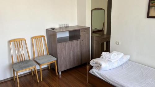 a small bedroom with a bed and two chairs at отель Voyage in Shymkent