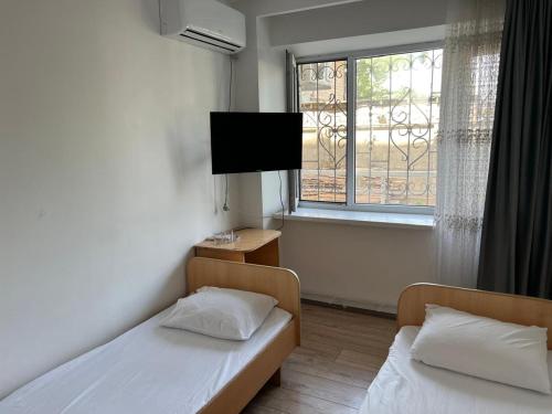a room with two beds and a tv and a window at отель Voyage in Shymkent