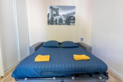 - un lit bleu avec 2 oreillers jaunes dans l'établissement Studio proche centre et gare, à Parthenay